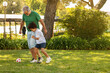 © Prostock-studio - Happy black small boy and european old man with beard play at ball, at football in park, outdoor