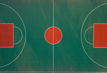 Aerial top view of an empty basketball court in green and red colors