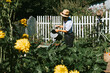 cute farmer boy watering plants from a metal watering can in kitchen garden vegetables, eco-friendly food from garden, rich autumn harvesting