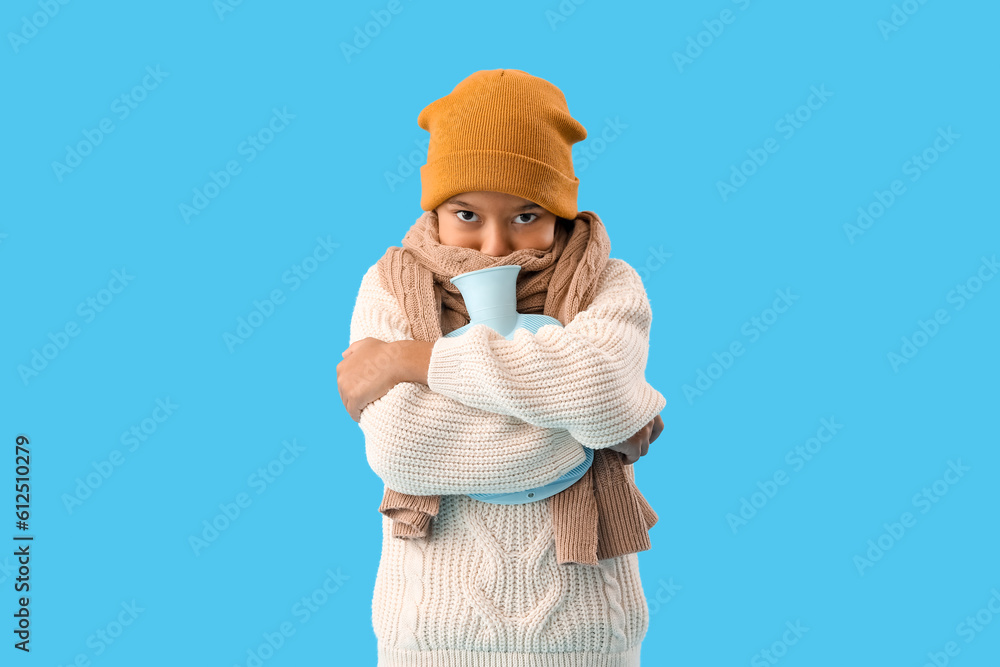 Frozen African-American boy with hot water bottle on blue background