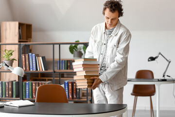 Wall Mural - Young man with stack of books in library