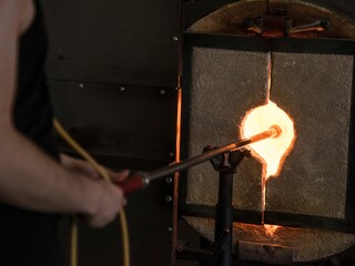 Poster - Glass blower holding glass mold with high temperature fire for shaping at workplace