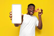© Богдан Маліцький - happy african american man in white t-shirt holding pizza box and showing empty smartphone screen