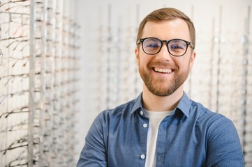 Poster - Shot of a handsome bearded man trying on new glasses at the eyewear store.Man buying glasses.Health, eyesight, vision, fashion, shopping