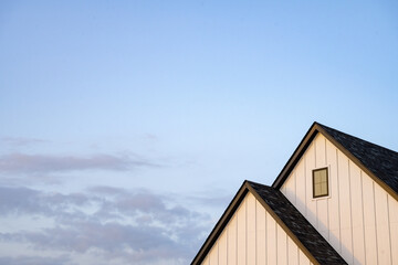 two peaks of white house with dark roof under blue sunset sky