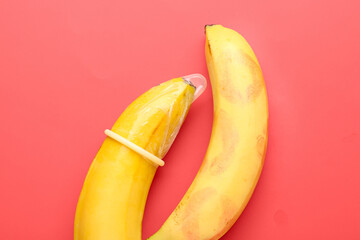 Bananas with lipstick kiss marks and condom on red background. Sex concept