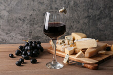 Glass With Red Wine And Pieces Of Tasty Cheese On Table