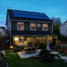 New York House At Night With All The Lights On. In This Eco-conscious And Beautifully Designed Backyard, The Presence Of Solar Panels Adds A Touch Of Sustainability And Innovation To An Already Captiv