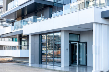 new building facade , windows and house entrance on apartment house exterior