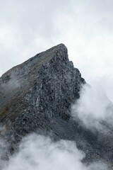 Wall Mural - Vertical shot of a peak of a rocky mountain on a foggy day