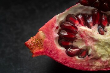 Poster - Macro shot of a piece of a pomegranate with juicy seeds, on a black background