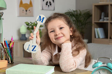 Wall Mural - Cute little girl studying with set of letters at home