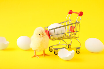 Wall Mural - Shopping cart with cute little chick and eggs on yellow background