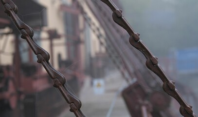 Closeup of metallic chains against a blurred view of a constuction site