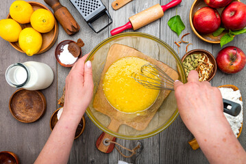 female cook beats eggs in a glass bowl with a whisk. Cooking dough for a pie top view. Cream with eggs in glass bowl