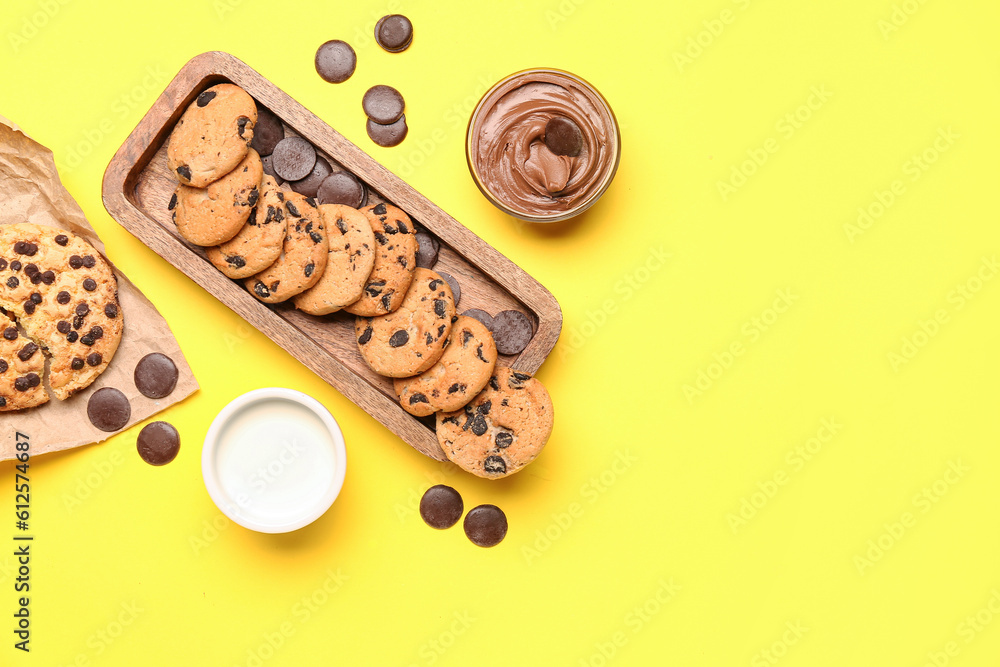 Cookies with chocolate and milk on yellow background
