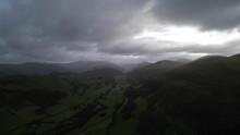 Drone view of a beautiful green countryside against the mountains on a gloomy day