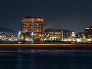 Closeup view of buildings and skyscrapers on the coast of an ocean during nighttime