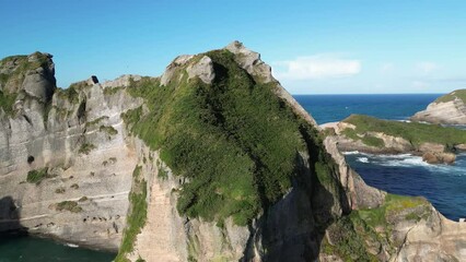 Poster - Aerial view of rocks and green forests by the sea on a sunny morning