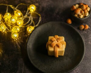 Sticker - Hazelnut praline in black plate and garland lights next to it on the table with small bowl