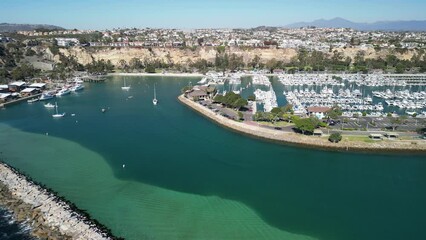 Wall Mural - Aerial view of a rocky pathway in the blue sea and boats in harbor on a summer day