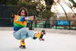 © Nano - bella mujer latina sonriendo, con frenillos, maquillaje y en patines con polera de arcoíris lgbtq en la calle practicando patinaje