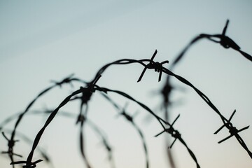 Closeup shot of a barbed wire on a blue sky background