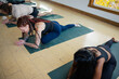 © Rob and Julia Campbell/Stocksy - Woman smiling and enjoying group yoga class in pigeon pose.