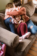 © Serena Burroughs/Stocksy - Mother hugging her happy smiling daughters on couch