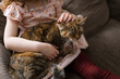© Serena Burroughs/Stocksy - Girl petting her cat while sitting on couch