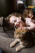 © Serena Burroughs/Stocksy - Girl petting her cat while sitting on couch