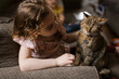 © Serena Burroughs/Stocksy - Girl petting her cat while sitting on couch