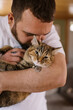© Serena Burroughs/Stocksy - Man hugging and cuddling his cat in his home
