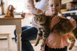 © Serena Burroughs/Stocksy - Cute happy toddler girl holding up her pet cat at home in kitchen