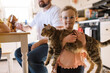 © Serena Burroughs/Stocksy - Cute happy toddler girl holding up her pet cat at home in kitchen