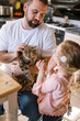 © Serena Burroughs/Stocksy - Father and daughter holding cat together while talking in kitchen