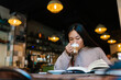 © Ezequiel Giménez/Stocksy - Focused woman drinking coffee and reading book in cafe