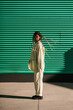 © Ezequiel Giménez/Stocksy - Stylish woman with braids near striped green wall