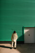 © Ezequiel Giménez/Stocksy - Stylish woman standing near green wall