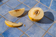 © Jarusha Brown/Stocksy - Sliced yellow melon on blue tiles in the sun.