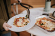 © Jarusha Brown/Stocksy - Woman serves a portion cooked lasagna from a tray.