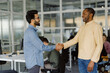 © Oleksii Syrotkin/Stocksy - Office colleague greeting partnership achievement