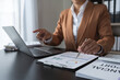 © Phimwilai - Businesswoman analyzing income charts and graphs with laptop computer. business analysis and strategy concept Business statistics, profit, financial growth rate on graph paper. financial data chart