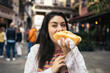 © Pedro Merino/Stocksy - Young woman visiting Madrid eating a typical calamari sandwich.