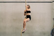 © Daniel Zapata/Stocksy - Woman climbing the rope in the gym.