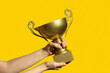 © Pixel Stories/Stocksy - Winner holding golden cup. Success and achievement, victory concept.