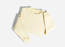 A folded yellow sweat shirt on a light grey background.