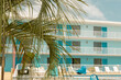 © Maryanne Gobble/Stocksy - Motel Exterior with Palm Tree and Blue Sky
