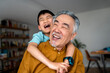 © Santi Nuñez/Stocksy - Grandson embraces laughing grandfather in cozy home.