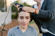 © ByLorena/Stocksy - Happy teenager boy giving buzz cut in property
